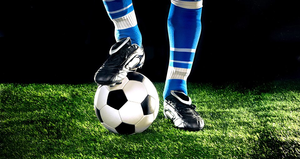 Beine eines Fußballers mit Ball